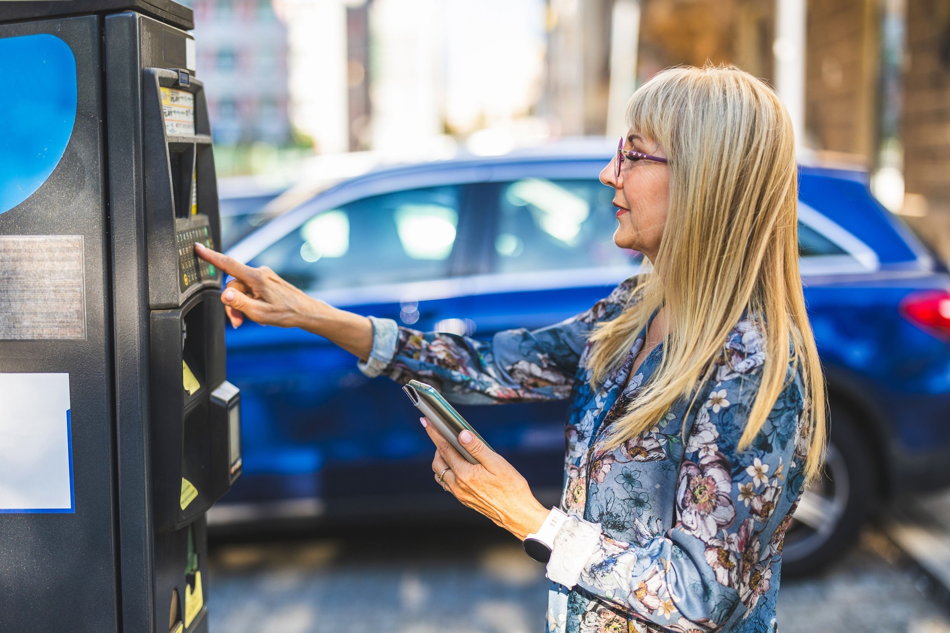 Mature woman using a mobile phone to pay for parking in the city